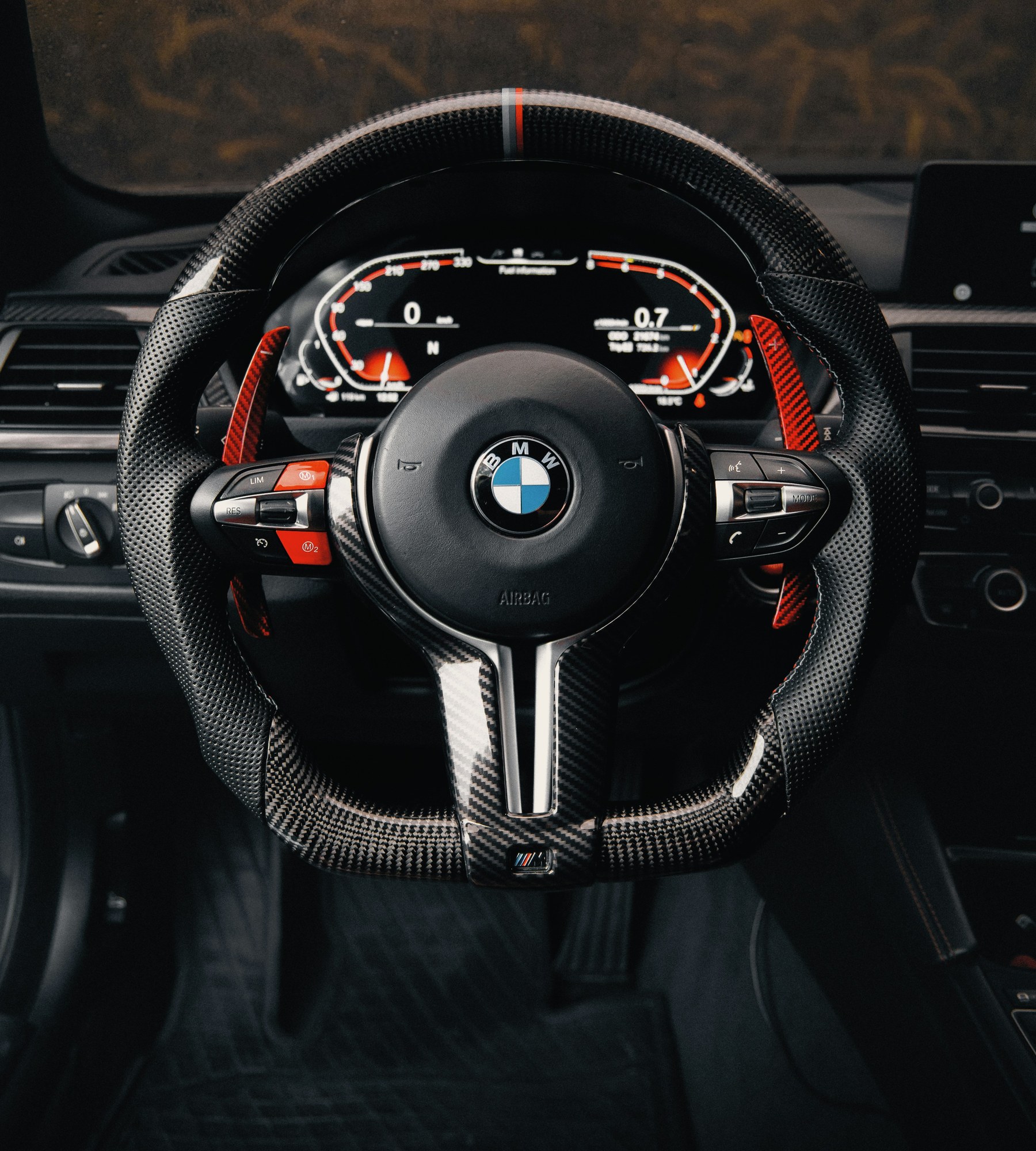 Carbon fiber steering wheel with perforated leather grips and a 12 o'clock stripe, in a BMW